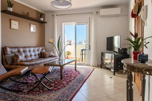 a living room with a leather couch and a television at Penthouse Olhão with terrace in Olhão