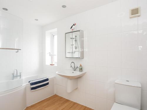a white bathroom with a sink and a toilet at Awel Y Mor in Pwllheli