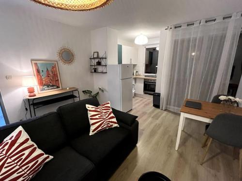 uma sala de estar com um sofá preto e uma cozinha em Le lac du pigeonnier em Colomiers