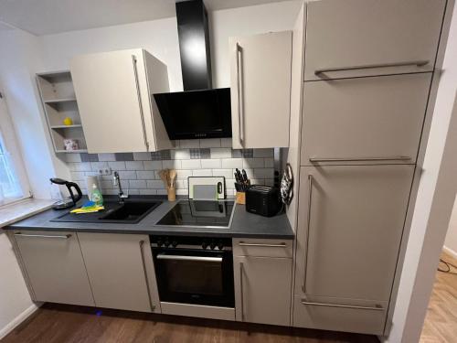 La cuisine est équipée de placards blancs et d'un réfrigérateur en acier inoxydable. dans l'établissement Apartment BERNSTEIN ruhig, familienfreundlich mit Garten, à Rostock