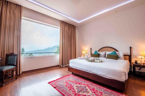 1 dormitorio con cama grande y ventana grande en The Fern Surya Resort Kasauli Hills, Dharampur, en Kasauli