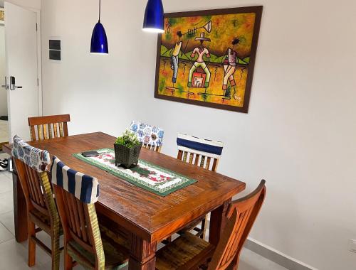 a dining room table with chairs and a painting on the wall at Apt Familiar-Condomínio fechado UBATUBA in Ubatuba