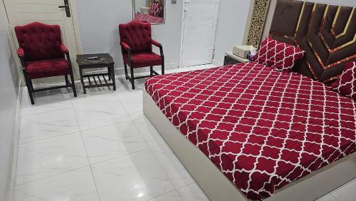 卡拉奇的住宿－Rose Palace Hotel Karachi，一间卧室配有一张床和两张红色椅子