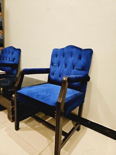 een blauwe stoel naast een muur bij Rose Palace Hotel Karachi in Karachi