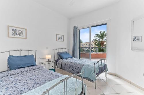 a bedroom with two beds and a balcony at Limnaria Gardens Cozy Apartment in Paphos City
