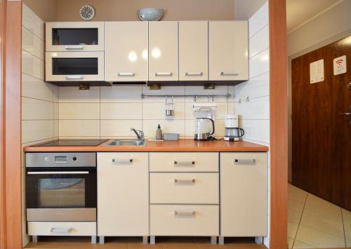 a kitchen with white cabinets and a sink at RentPlanet - Apartament Bałtycka in Kołobrzeg