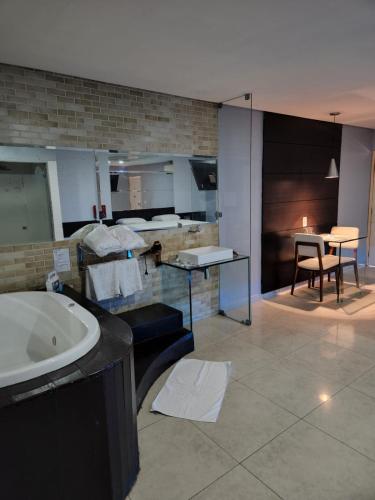 a bathroom with a tub and a table and a dining room at Status Motel Perimetral Adults Only in Olinda