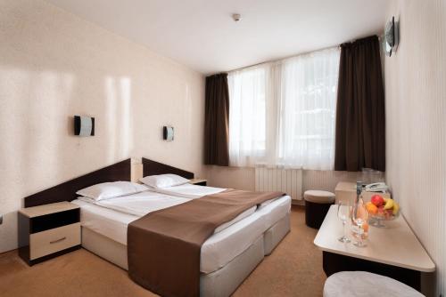 ein Hotelzimmer mit einem großen Bett und einem Tisch in der Unterkunft Balneocomplex Kamena in Welingrad