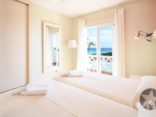 a white bedroom with two beds and a view of the ocean at Apartamento 5 en Primera linea de mar in Santo Tomás