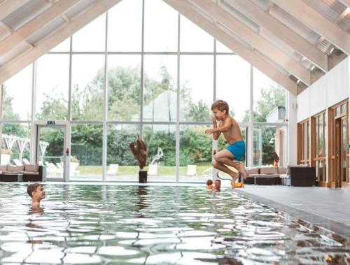 a man jumping into the water in a swimming pool at Cotswold Cottage Sleeps 7 pool/sports/spa/walks in Somerford Keynes