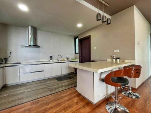 a kitchen with white cabinets and a counter with a bar at Cozy Homestay Vivacity Megamall in Kuching