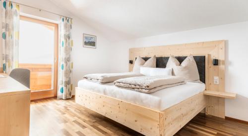 a bedroom with a bed with a wooden headboard at Brennergut Ferienwohnung am Bauernhof in Mühlbach am Hochkönig