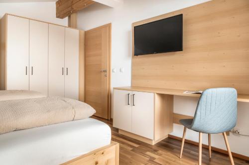 a bedroom with a desk and a tv on a wall at Brennergut Ferienwohnung am Bauernhof in Mühlbach am Hochkönig