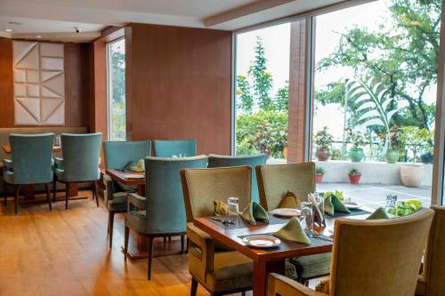 a restaurant with tables and chairs and a large window at The Fern Surya Resort Kasauli Hills, Dharampur in Kasauli