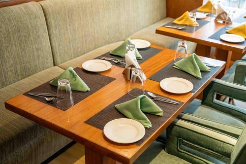 a wooden table with green napkins and plates on it at The Fern Surya Resort Kasauli Hills, Dharampur in Kasauli