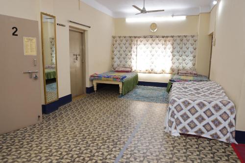 um pequeno quarto com 2 camas e uma janela em 1 Room for 4 Guests OR 2 BHK for 4 to 10 Guests with AC for Families em Hyderabad