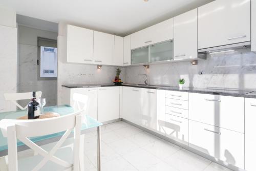 a white kitchen with white cabinets and a table at Host Wise - Gorgeous Spacious Flat - Ace Location in Porto