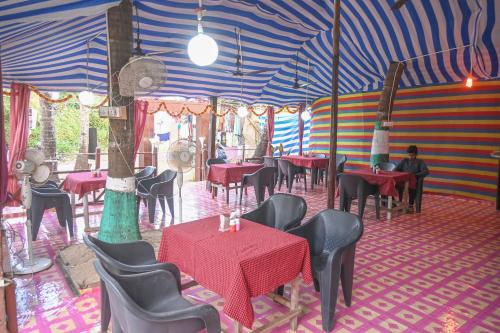 una tenda con sala da pranzo con tavoli e sedie. di Kashinath Beach Huts ad Agonda