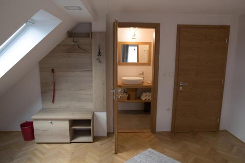 ein Bad mit einem Waschbecken und einer Tür in einem Zimmer in der Unterkunft Bed & Breakfast Dvorec in Petrovče