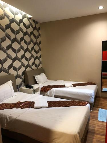 a hotel room with three beds in a room at M BOUTIQUE INN (BINTANG JAYA) in Miri