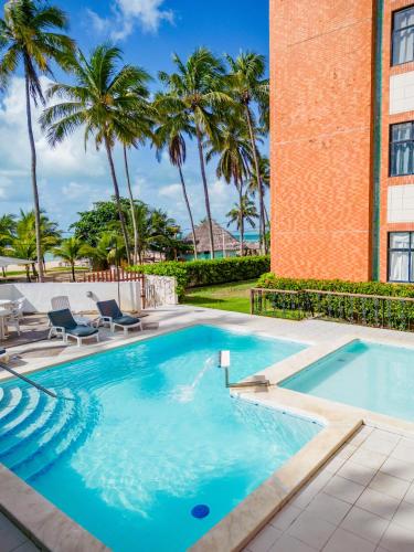 a swimming pool with chairs and palm trees at Moriah Maceió Beach Hotel in Maceió