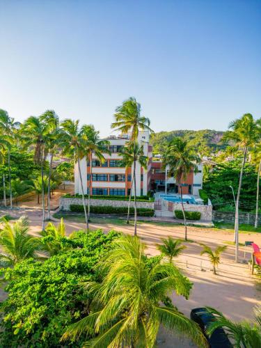a building with palm trees in front of it at Moriah Maceió Beach Hotel in Maceió