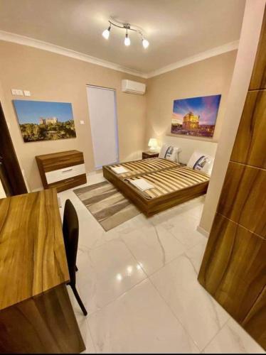 ein großes Schlafzimmer mit einem Bett und einem Tisch in der Unterkunft Marsaskala 1 bedroom penthouse in Marsaskala