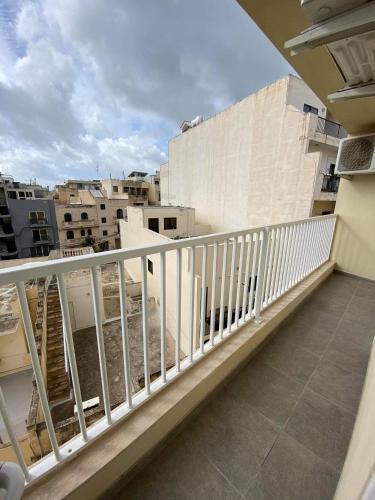 einen Balkon mit weißem Geländer und Gebäuden in der Unterkunft Marsaskala 1 bedroom penthouse in Marsaskala