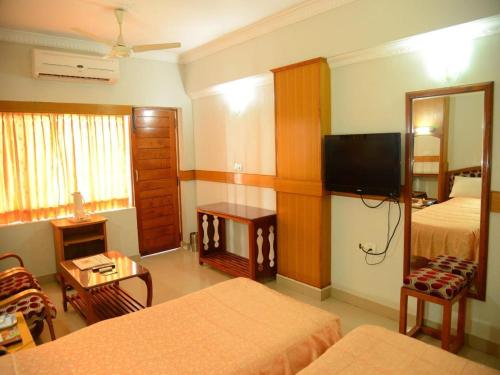 a hotel room with two beds and a television at Hotel City Tower in Coimbatore