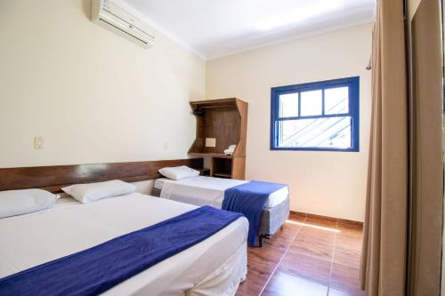 a hotel room with two beds and a window at Mirante Praia Hotel in Olímpia