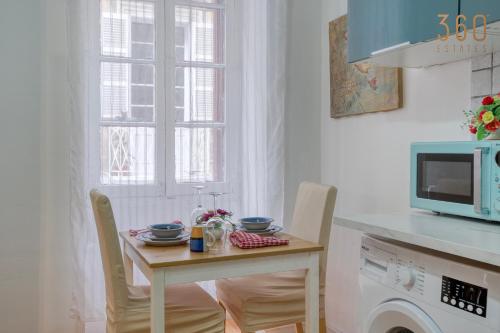 a kitchen with a small table with chairs and a microwave at Sweet Stay Floriana Studios in Il-Furjana