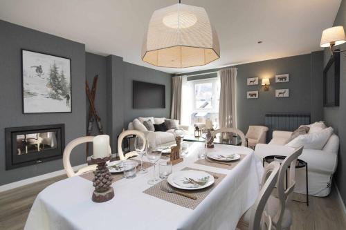 a dining room and living room with a white table and chairs at El Ciervo de Santa María by BeValle in Panticosa