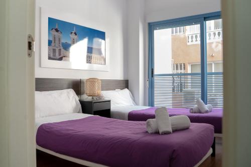 a bedroom with two beds with purple sheets and a window at Apartamento Cerca de la playa in Benidorm