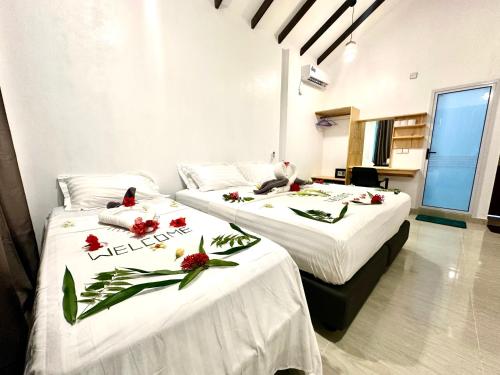 two beds in a room with flowers on them at Thoddoo Island Life in Thoddoo