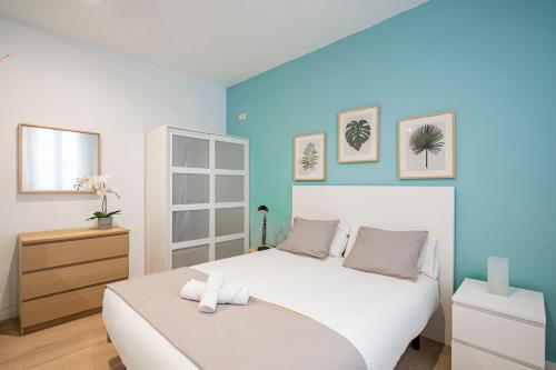 マドリードにあるHomelike Las Letrasの白いベッドと青い壁が備わるベッドルーム1室が備わります。