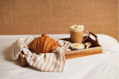 a tray of croissants and a cup of coffee on a bed at Amsterdam Lake Hotel in Badhoevedorp