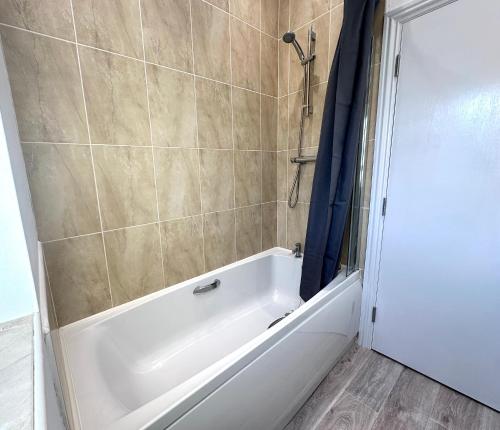 uma banheira branca na casa de banho com um chuveiro em Wallis House by Blue Skies Stays em Stockton-on-Tees