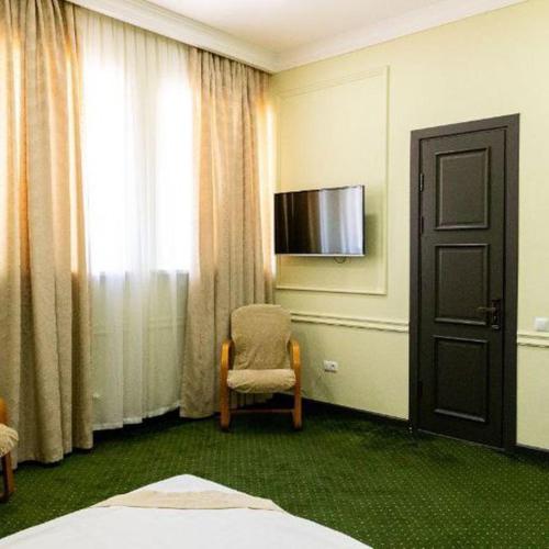 Cette chambre comprend un lit, une chaise et une télévision. dans l'établissement OA Tashkent, à Qŭyliq