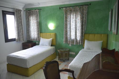 2 camas en una habitación con paredes verdes en Riad Baddi en Sale