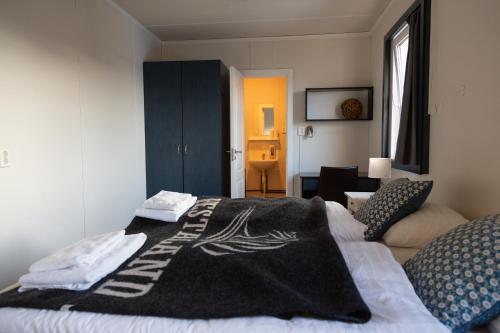 a bedroom with a bed with a black blanket on it at Hestaland Guesthouse Horse Farm Stay in Staðarhús