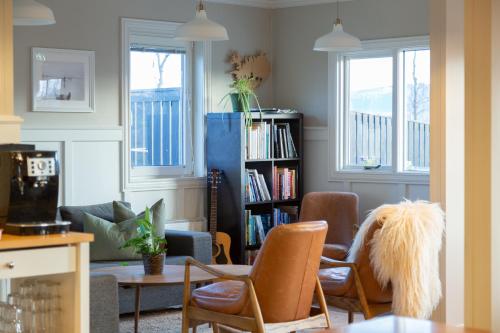 een woonkamer met stoelen en een boekenplank bij Hestaland Guesthouse Horse Farm Stay in Staðarhús