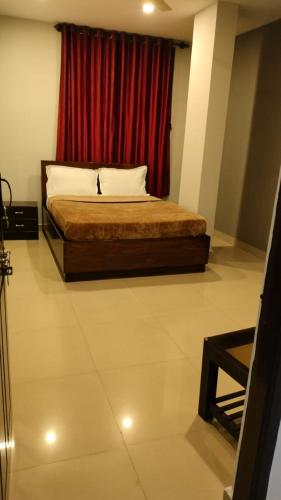 1 dormitorio con 1 cama con cortina roja en Town gate en Madikeri