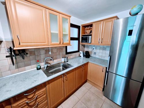 a kitchen with wooden cabinets and a stainless steel refrigerator at Residence Ocean View in Mogán