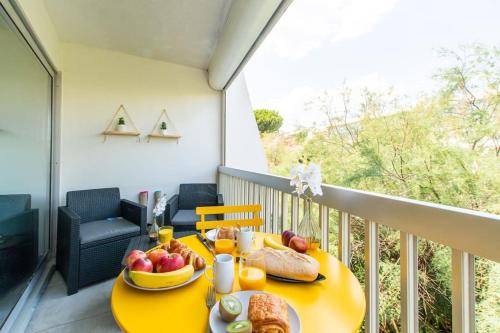 une table jaune avec de la nourriture sur un balcon dans l'établissement Chemin de la Plage*Clim* Plage à 5 min * Terrasse, à La Grande Motte