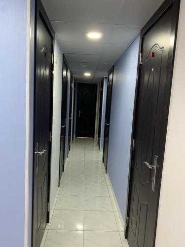 a hallway with black doors and a tile floor at Bright Rooms in Dubai