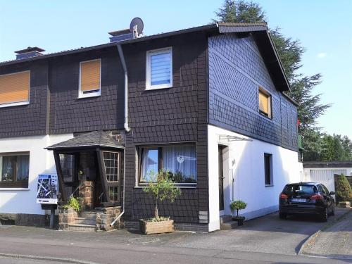 a black and white house with a car parked in front at Ferienwohnung Prinz in Lindlar