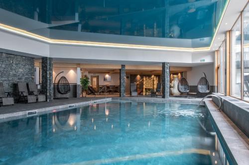 a large swimming pool in a hotel with a building at CGH Résidences & Spas Alpaga in La Toussuire