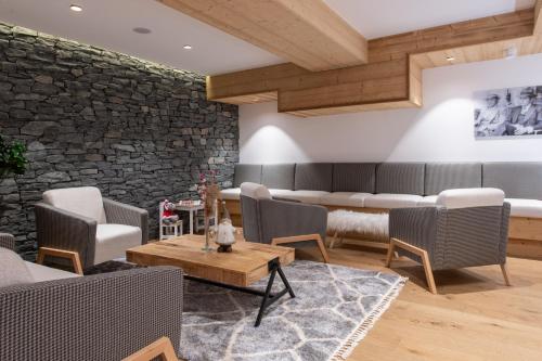 - un salon avec des chaises, des tables et un mur en pierre dans l'établissement CGH Résidences & Spas Alpaga, à La Toussuire