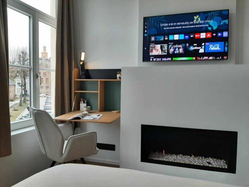 1 dormitorio con escritorio y TV encima de una chimenea en B&B Anna's, en Brujas