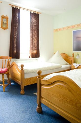 a bedroom with two beds and a chair and a window at Pension Am Alten Markt in Halle an der Saale